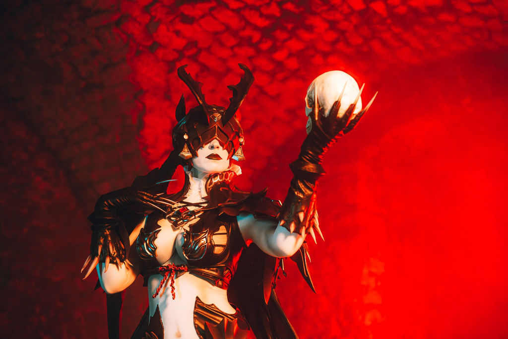 An armored succubus holding a skull against a saturated red wall